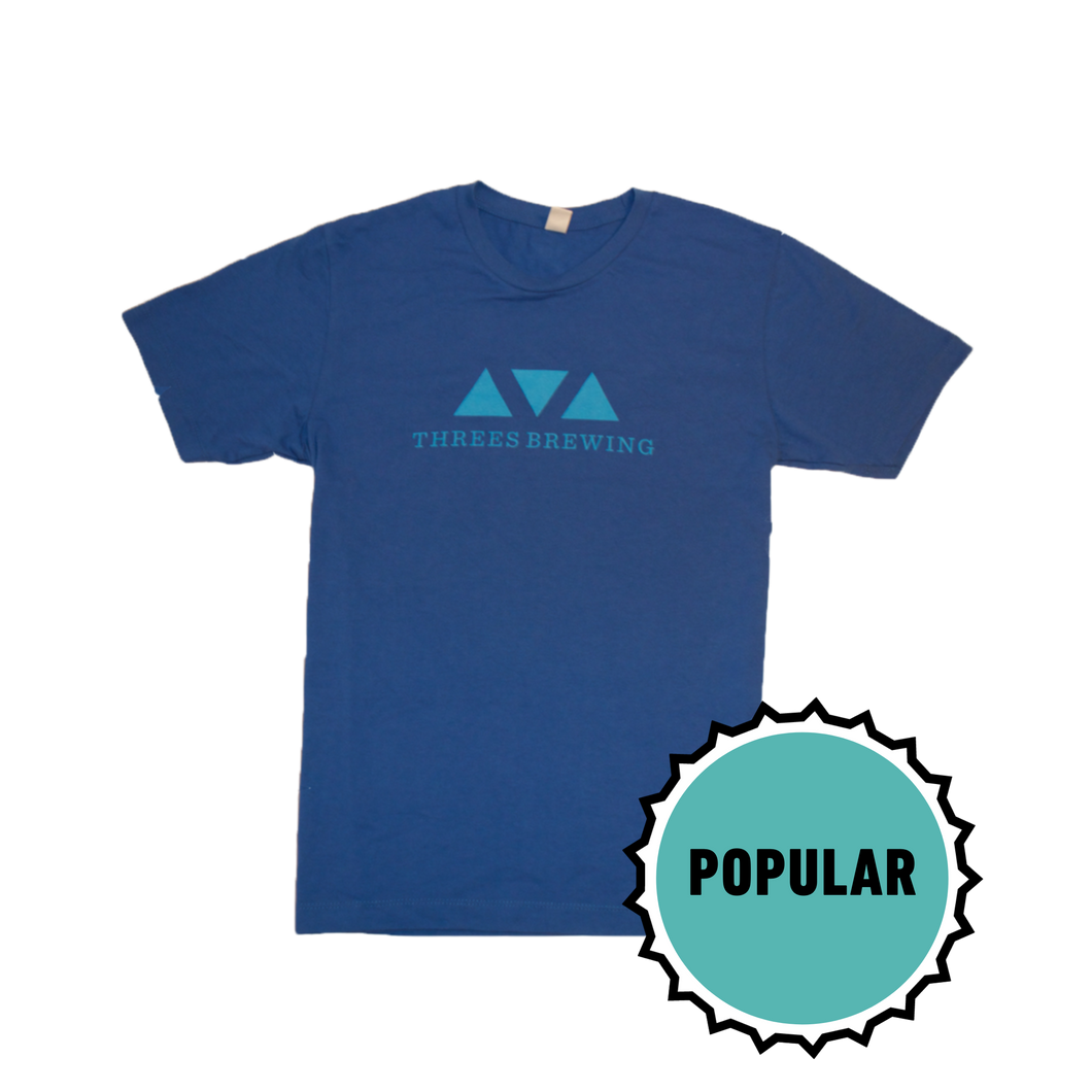 Blue t shirt with lighter blue Threes logo. Image is badged with text that says 