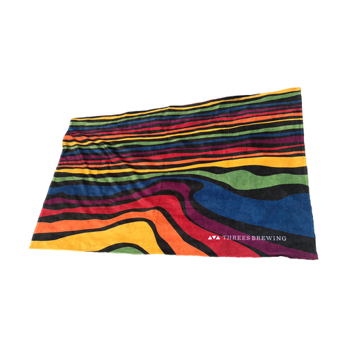 Beach towel with rainbow waves pattern and Threes logo