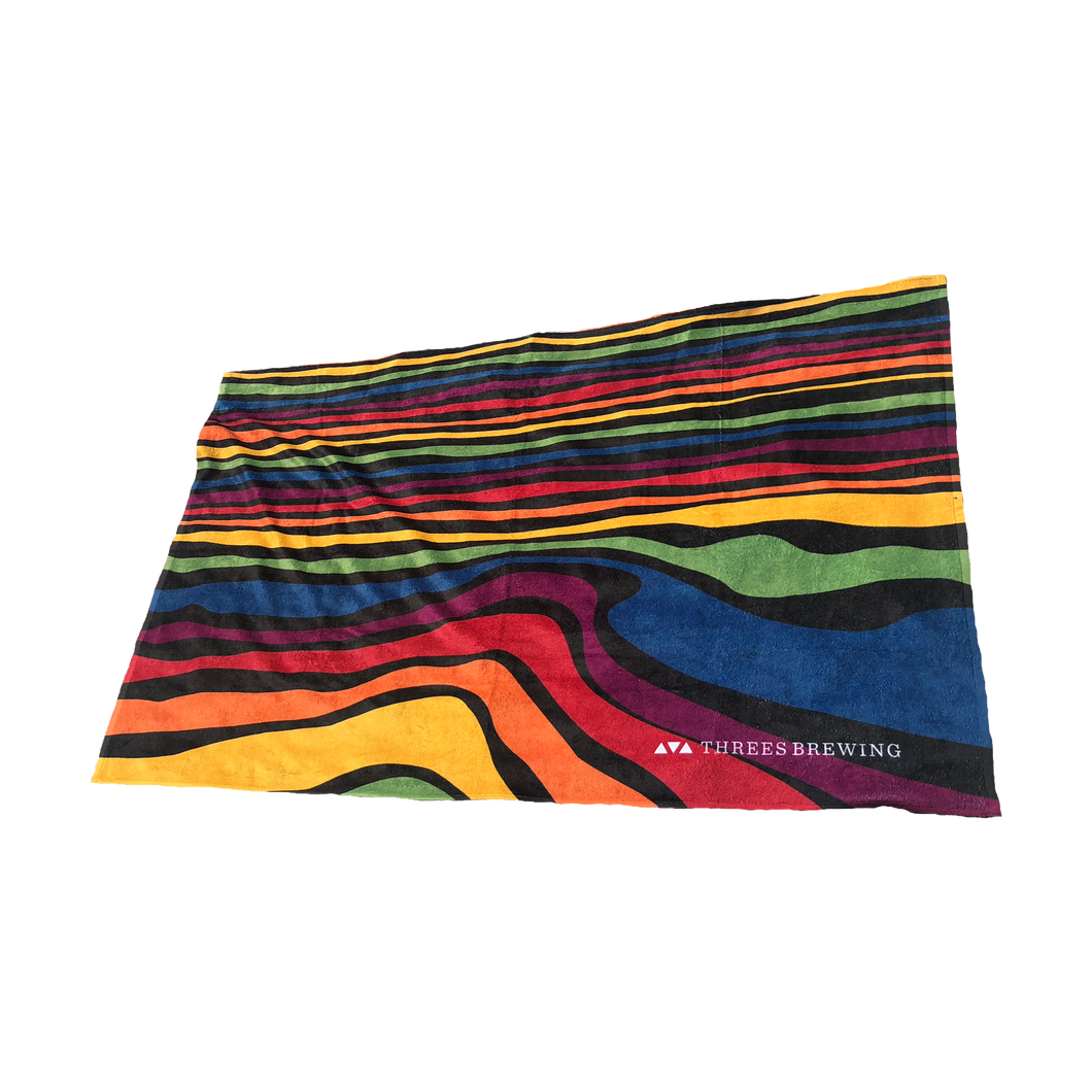 Beach towel with rainbow waves pattern and Threes logo